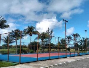 a tennis court behind a fence with palm trees at Casa em Praia do Flamengo /Salvador-Ba in Salvador