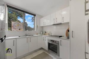 cocina blanca con armarios blancos y ventana en Entire unit in Hurstville, en Sídney
