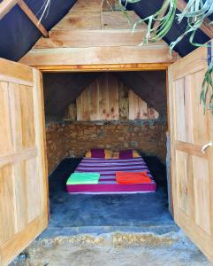 łóżko w drewnianym domu z otwartymi drzwiami w obiekcie Eco Lodge Haputale-Camping Sri lanka w mieście Haputale