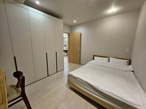 a bedroom with a large white bed and a chair at IMSTAY friendly child Eoeum Aewol in Jeju
