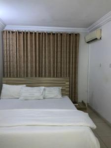 - une chambre avec un lit blanc et une grande fenêtre dans l'établissement DBI GUEST HOUSE, à Lagos