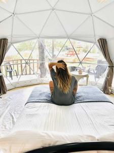 Balilihan的住宿－Eco Glamping Treehouses Closest Resort To All Tourist Attractions，坐在帐篷里的床上的女人