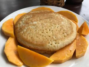 a white plate with a pancake and slices of orange slices at Eden House & Coffee Con Dao in Con Dao