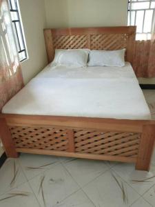 a bed in a room with a wooden bed frame at 4 BR/5 Bathroom Bungalow in Boma la Ngombe
