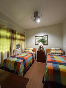 1 dormitorio con 2 camas, mesa y ventana en All Care Bed and Breakfast en Tagaytay