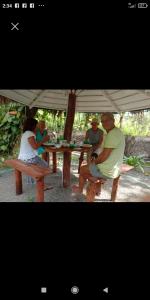 un grupo de personas sentadas en una mesa de picnic bajo un paraguas en My House Ahangama en Ahangama