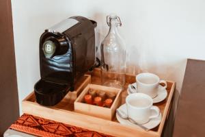 una macchinetta del caffè e tazze su un vassoio di legno di ALON CLOUD9, beach front a Catangnan