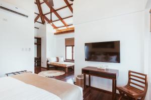 a bedroom with a bed and a desk and a tv at ALON CLOUD9, beach front in Catangnan