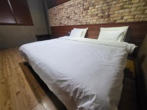 a large white bed in a bedroom with a brick wall at Mokhwa Motel in Icheon