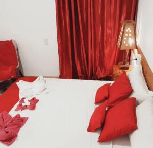 a bedroom with a bed with red and white pillows at Hostel Damaris in Puerto Iguazú