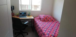 1 dormitorio con escritorio, 1 cama y ordenador portátil en casa con habitaciones disponibles, estacionamiento privado, patio y áreas comunes para compartir en Puerto Montt
