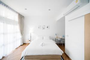 a white bedroom with a bed and a table at Mitt Haus (Lat Phrao Soi 5) in Bang Su