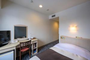 a hotel room with a bed and a desk and a tv at Kotoni Green Hotel in Sapporo