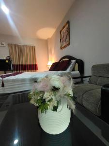 a vase with flowers on a table in a hotel room at The rich room ห้องพักนครราชสีมาใกล้เซ็นทรัล in Nakhon Ratchasima