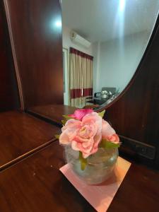 a vase with a pink rose sitting on a table at The rich room ห้องพักนครราชสีมาใกล้เซ็นทรัล in Nakhon Ratchasima