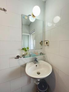 a white bathroom with a sink and a mirror at The Nest Homestay in Ho Chi Minh City