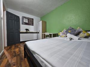1 dormitorio con 1 cama grande y pared verde en Spitalfields Rooms, en Londres