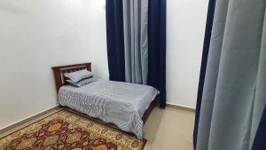 - une chambre avec un lit, un tapis et des rideaux dans l'établissement D'Lofa Homestay, à Bachok