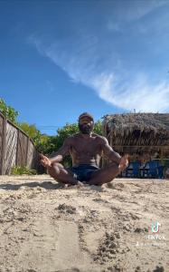 un homme assis sur la plage qui fait de la méditation dans l'établissement Punta Arena EcoHostal & EcoFit - Your Eco-Friendly Oasis, à Playa Punta Arena