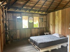 1 dormitorio con 1 cama en una habitación de madera en Punta Arena EcoHostal & EcoFit - Your Eco-Friendly Oasis, en Playa Punta Arena