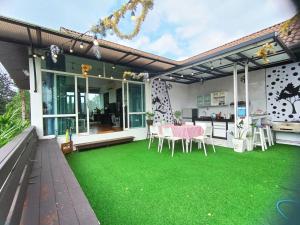 a patio with a green lawn in front of a house at Krabi River Cottage Pool Villa in Ban Krabi Yai