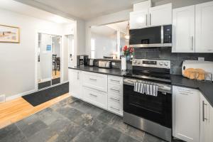 a kitchen with white cabinets and black appliances at V-Home by Heritage park and Glenmore Reservoir in Calgary