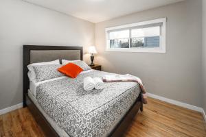 a bedroom with a bed with orange pillows and a window at V-Home by Heritage park and Glenmore Reservoir in Calgary
