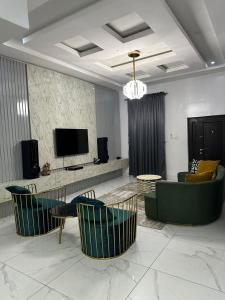 a living room with green chairs and a table and a television at Affordable luxury 3bed apartment in Maiyegun