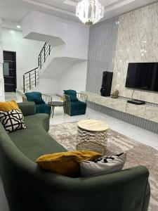 a living room with a green couch and a tv at Affordable luxury 3bed apartment in Maiyegun