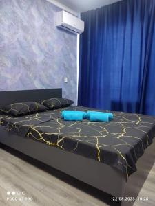uma cama com almofadas azuis e uma cortina azul em Уютная студия 65/3 em Almaty