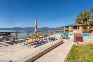 國王海灘的住宿－Luxurious Lakefront Condo with Lake Views in Brockway Springs Resort Close to Slopes，一组长椅和桌子,位于游泳池旁