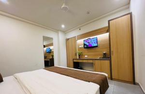 ein Hotelzimmer mit einem Bett und einem Flachbild-TV in der Unterkunft Hotel Venus By Mantram Hospitality in Rajkot