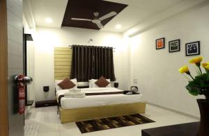 a bedroom with two beds and a ceiling fan at Hotel Crown in Rajkot