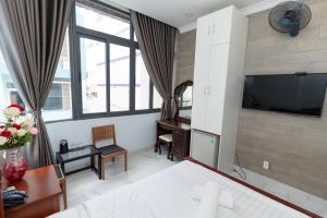 a bedroom with a bed and a desk and a tv at Sunny Guesthouse in Ho Chi Minh City