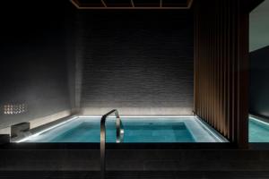 a hot tub in a bathroom with a shower at Nozo Hotel in Furano