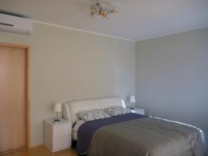 een witte slaapkamer met een bed en een lamp bij Aida Marina Apartment in Pärnu