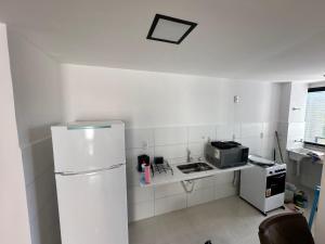 a white kitchen with a refrigerator and a microwave at Apartamento Para Temporada in Ilhéus