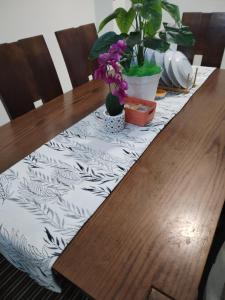 a table with a table cloth on a wooden table with flowers at Lekir baiduri homestay in Sitiawan