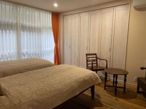 a bedroom with two beds and a chair and a window at La Classe Angel Road 2 - Vacation STAY 71507v in Fuchisaki