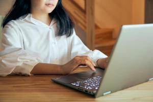 a woman sitting at a table using a laptop computer at 城崎温泉一棟貸しの宿　ゆっ蔵 in Toyooka