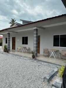 a white house with chairs and tables in it at D’solok chalet in Kampong Pantai Ayer Hitam