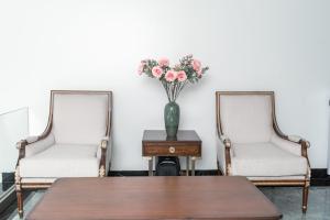 dos sillas y una mesa con un jarrón de flores en Quang Minh Riverside Hotel Danang en Da Nang