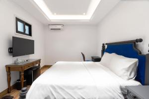 a bedroom with a white bed and a television at Quang Minh Riverside Hotel Danang in Danang