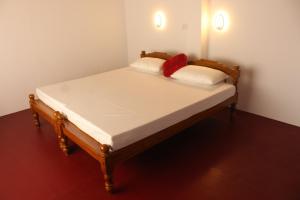 1 cama con 2 almohadas rojas en una habitación en Marari Sunset Beach Villa, en Alleppey