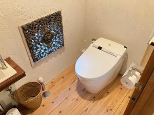 a bathroom with a white toilet and a wooden floor at Kaiza in Nanjo