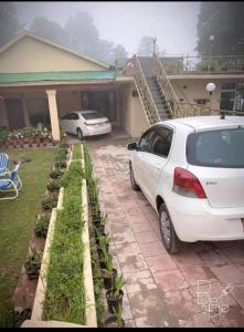 a white car parked in front of a house at Rashk e Qamar in Murree