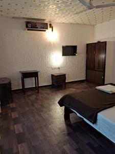 1 dormitorio con cama, mesa y TV en Surya Eco and Wedding Resort, en Trichūr