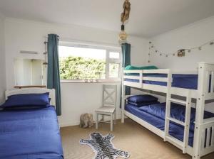 a bedroom with two bunk beds and a window at 27 Cae Du in Abersoch