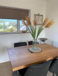a dining room table with a vase with a plant on it at 27 Cae Du in Abersoch