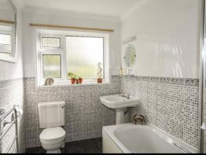 a bathroom with a toilet and a sink and a tub at 27 Cae Du in Abersoch